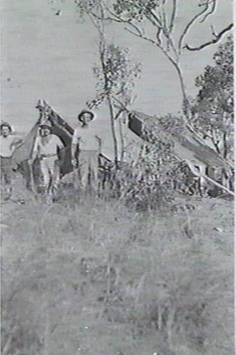 Three men standing outside some tents